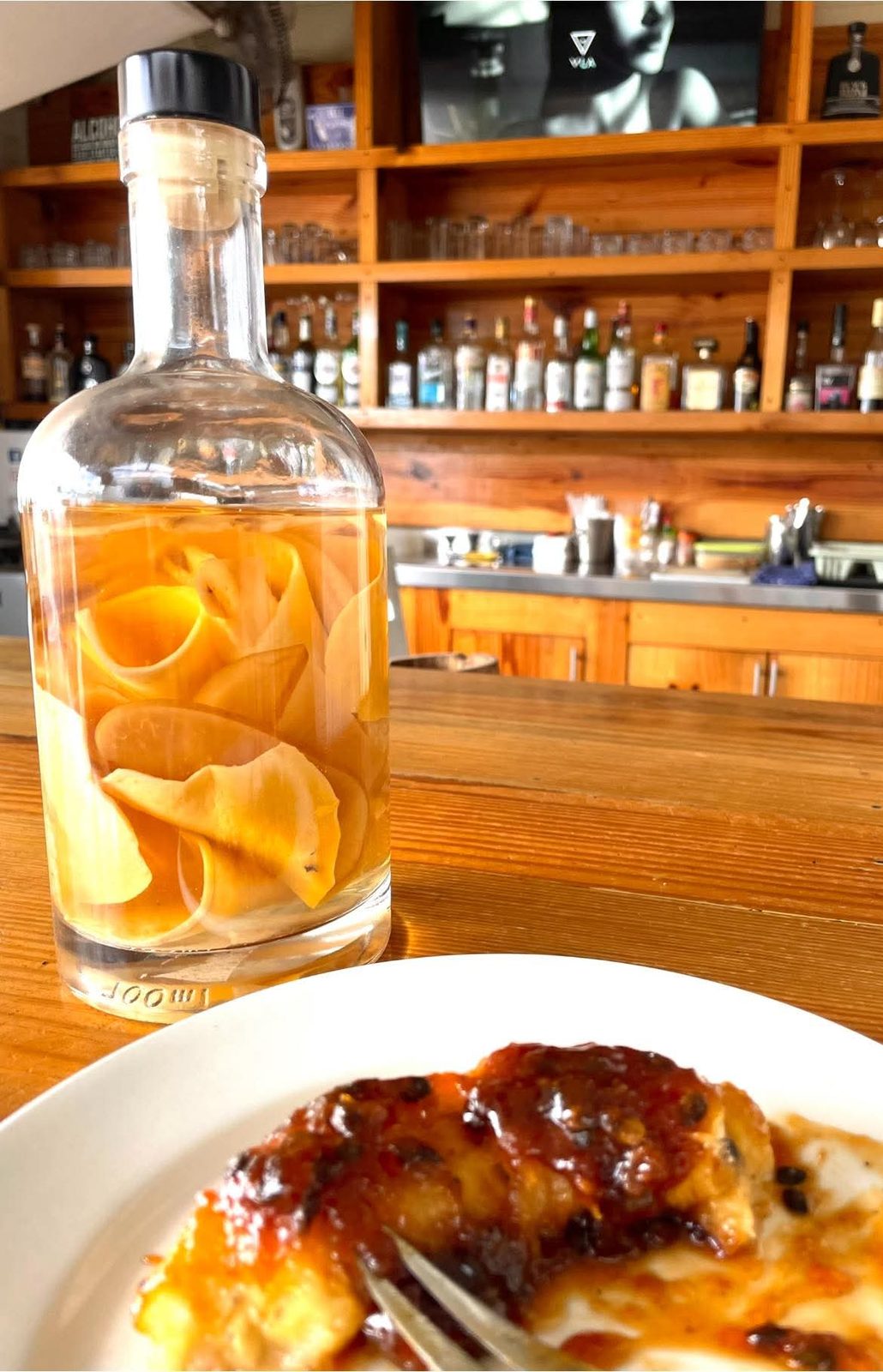 House-infused rum bottle and a plated dish