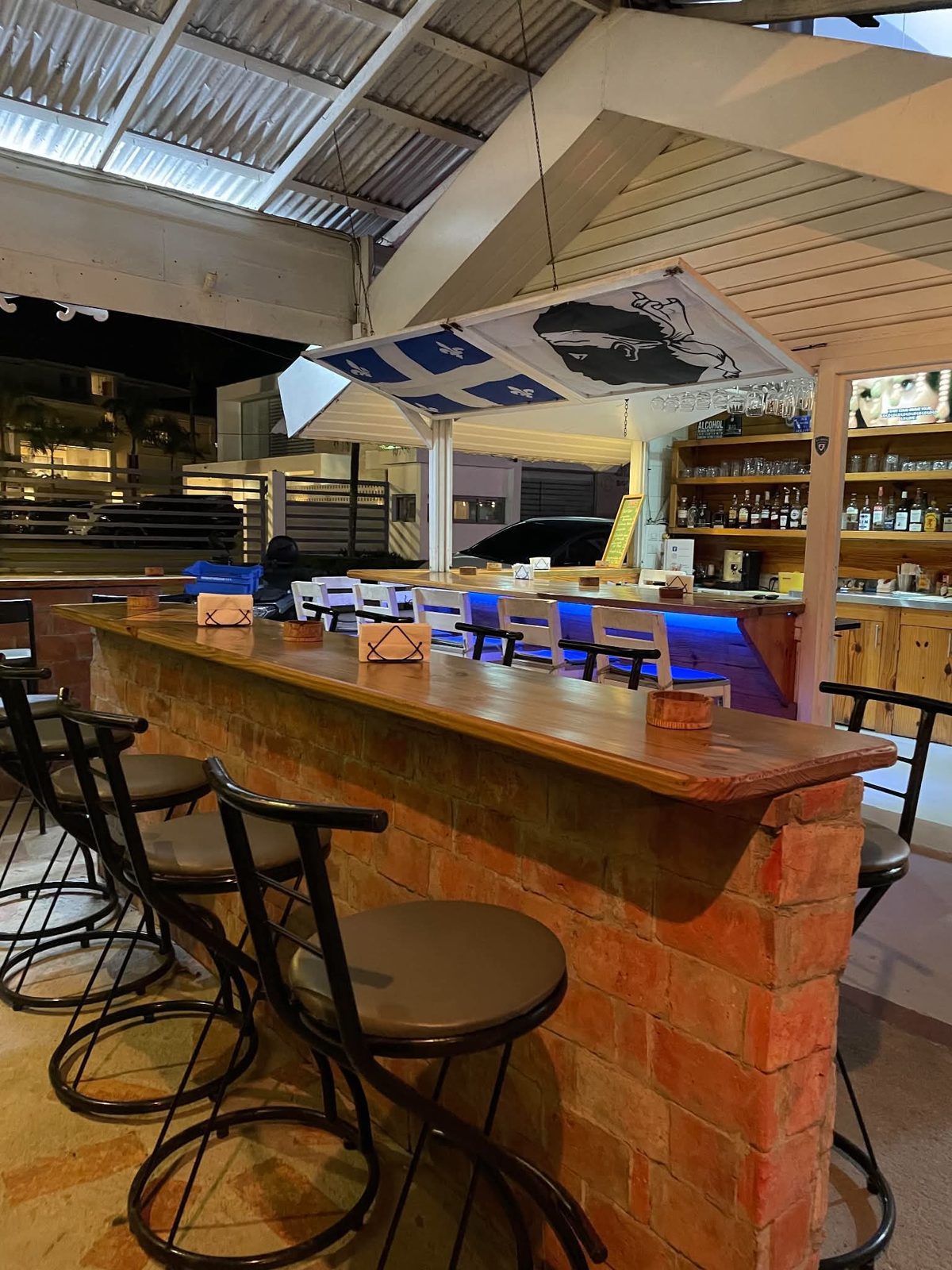 Sparrow's brick bar and white stools at night, under the Québec flag